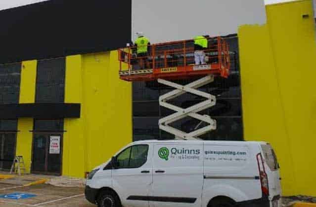 Factory exterior painted yellow with crane beside van