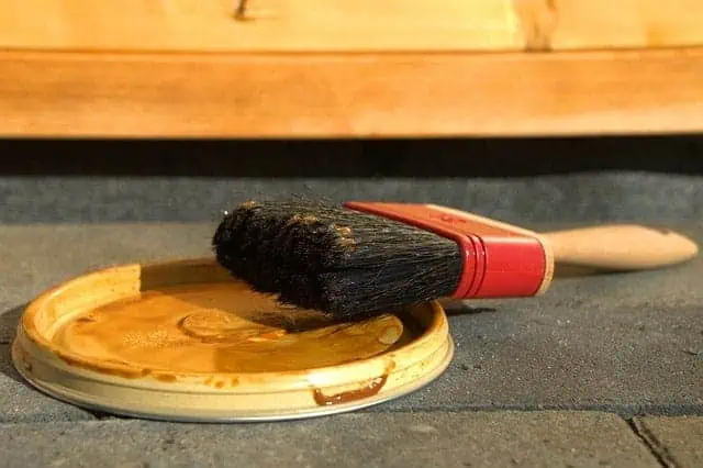 close up of a paint brush leaning on a paint lid