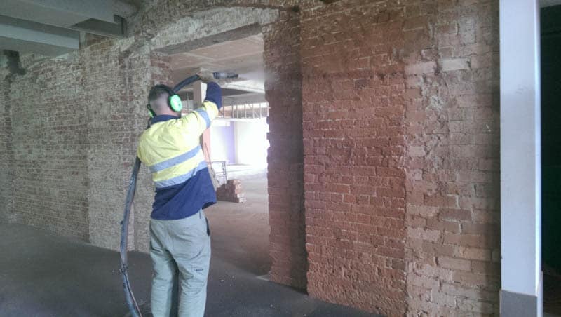 Cleaning brick wall by sandblasting